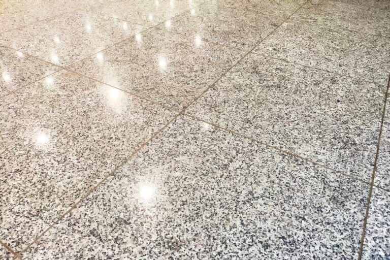 The tiles on the floor are shiny. Background, texture. Shiny Tiled Floor in Indoor Setting. Glossy surface reflects light on polished tiles