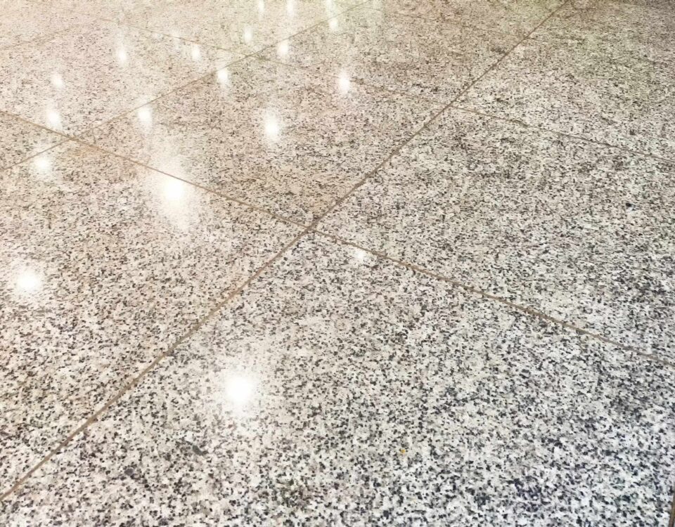 The tiles on the floor are shiny. Background, texture. Shiny Tiled Floor in Indoor Setting. Glossy surface reflects light on polished tiles