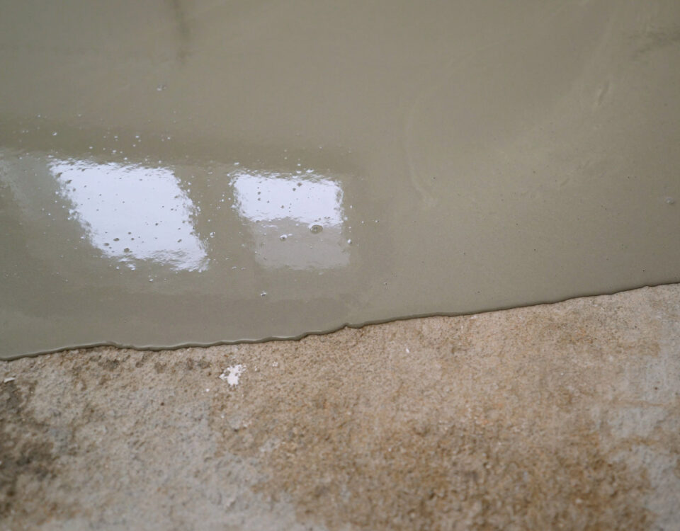 Applying epoxy resin on a concrete surface, creating a smooth and durable finish ideal for industrial and commercial settings