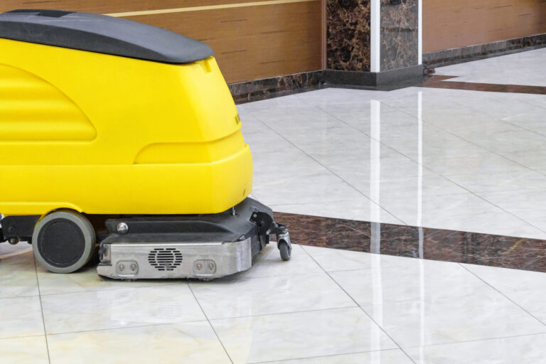Cleaning machine in an office lobby. Cleaned floor in the interior of company or luxury hotel. Yellow vacuum equipment for cleaning on a shiny marble floor. Concept of professional cleaning service.