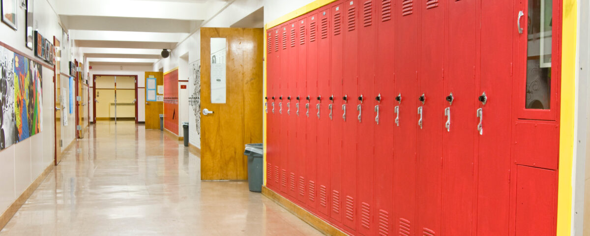 An empty highschool hallway with red lockers on the right side