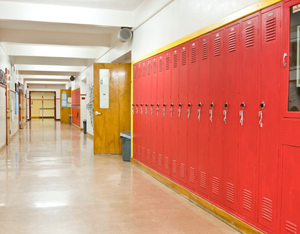 An empty highschool hallway with red lockers on the right side