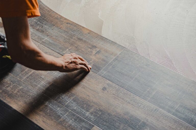 Construction worker installing luxury vinyl tiles in a modern apartment