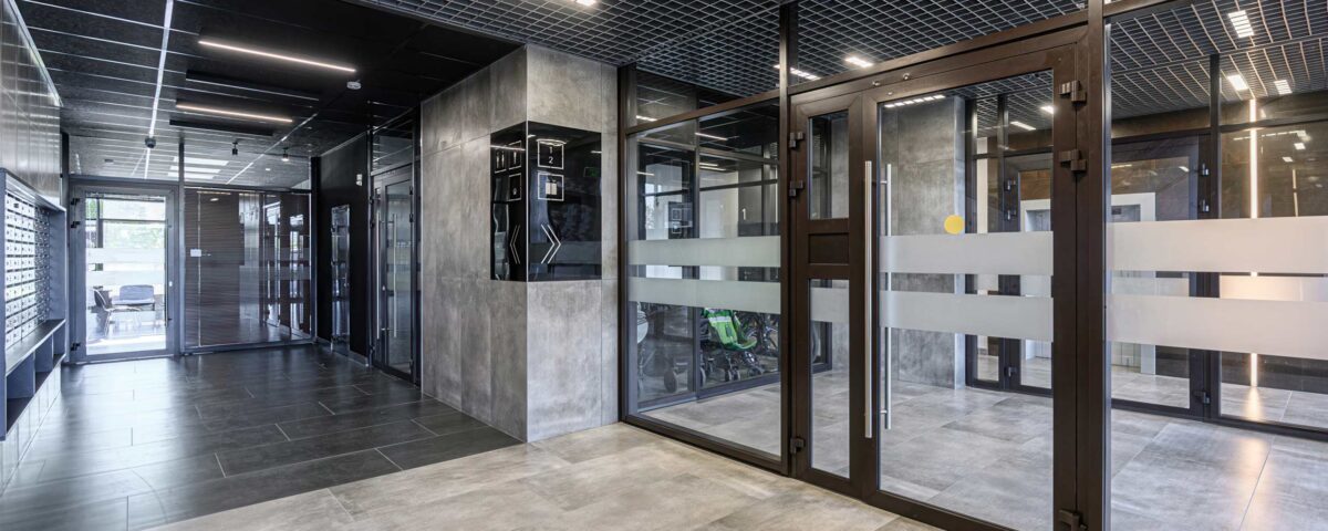 Modern lobby featuring tile floors, glass doors, a grid ceiling with lights, and a security system