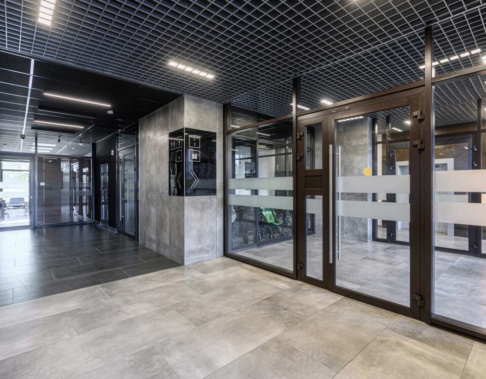 Modern lobby featuring tile floors, glass doors, a grid ceiling with lights, and a security system
