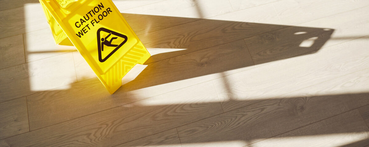 Wet Floor sign on clean freshly mopped slippery grey floor with sunlight and shadows