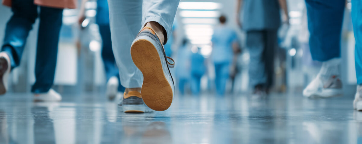 Healthcare workers in blue scrubs walking through a bright modern hospital hallway.