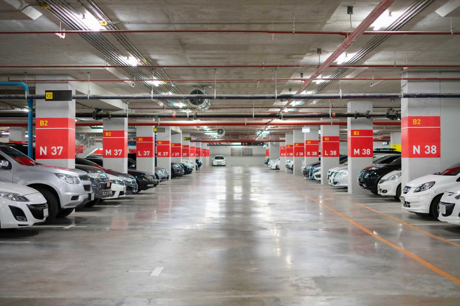 Commercial-Parking-Garage-Floor-Cleaning-and-Maintenance-Guide-for-Businesses Blurred Parking garage interior shot of multi-story car park, underground parking with cars.