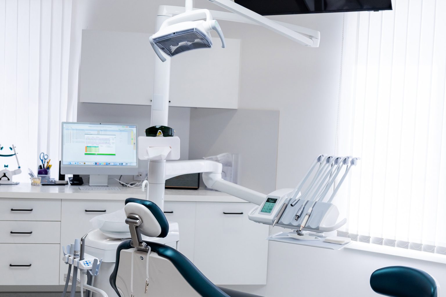Dental-office-floor-cleaning-and-infection-control-standards Modern empty dental treatment room with professional medical chair. Interior of a bright clean dental office featuring ergonomic chair, medical equipment, and white cabinet furniture.